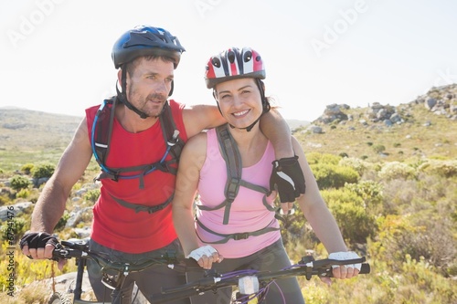 Fit cyclist couple smiling together on mountain trail