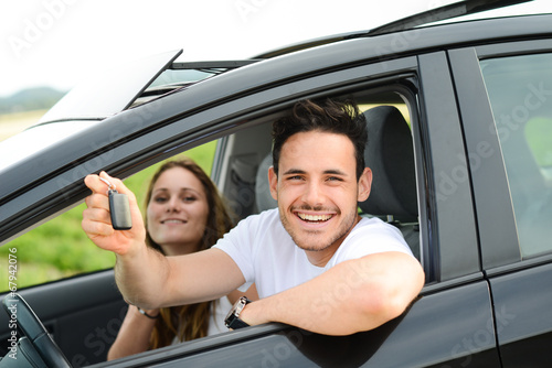 happy young couple driving new car on holiday trip in summer