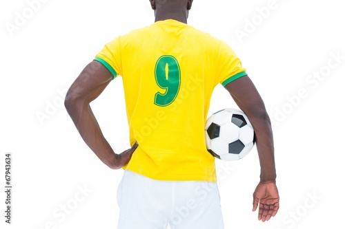 Football player in yellow standing with the ball