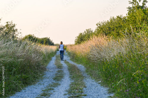 Woman walking at a gravel road at summer