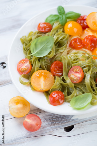 Glass plate with boiled tagliatelle, fried tomatoes and basil