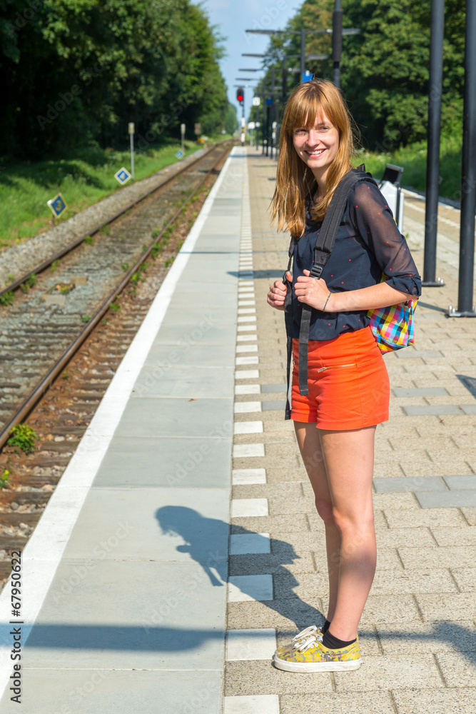 Girl standing at station waiting on train