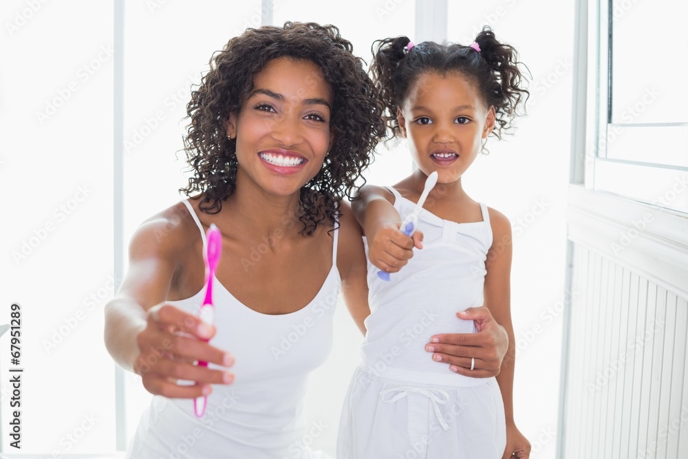 Pretty mother and daughter showing toothbrushes Pretty mother and daughter showing toothbrushes