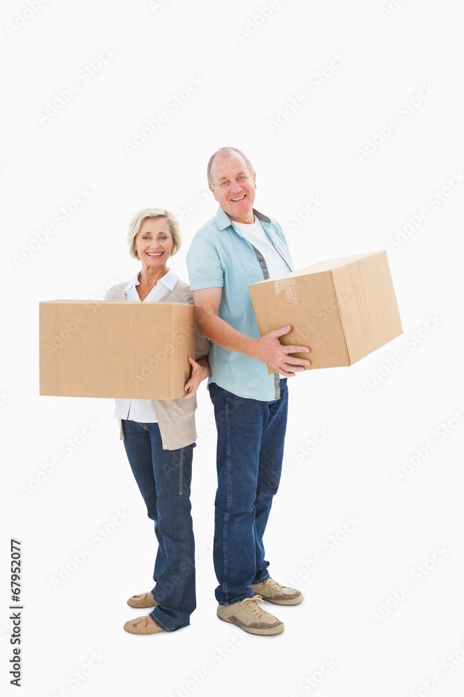 Older couple smiling at camera holding moving boxes Older couple smiling at camera holding moving boxes