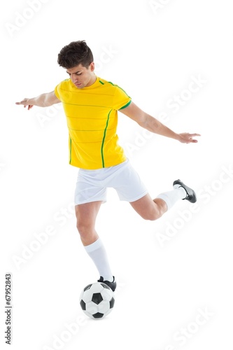 Football player in yellow jersey kicking ball