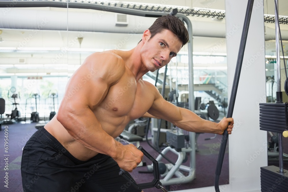Shirtless muscular man using resistance band in gym Shirtless muscular man using resistance band in gym