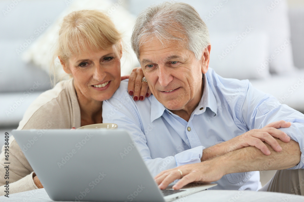 Senior couple websurfing on internet with laptop