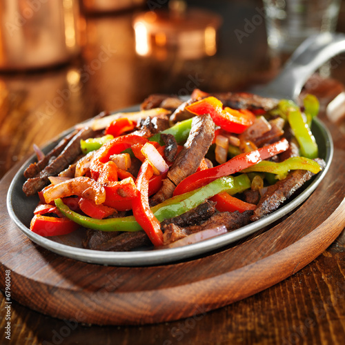 beef fajitas with green and red peppers in iron skillet