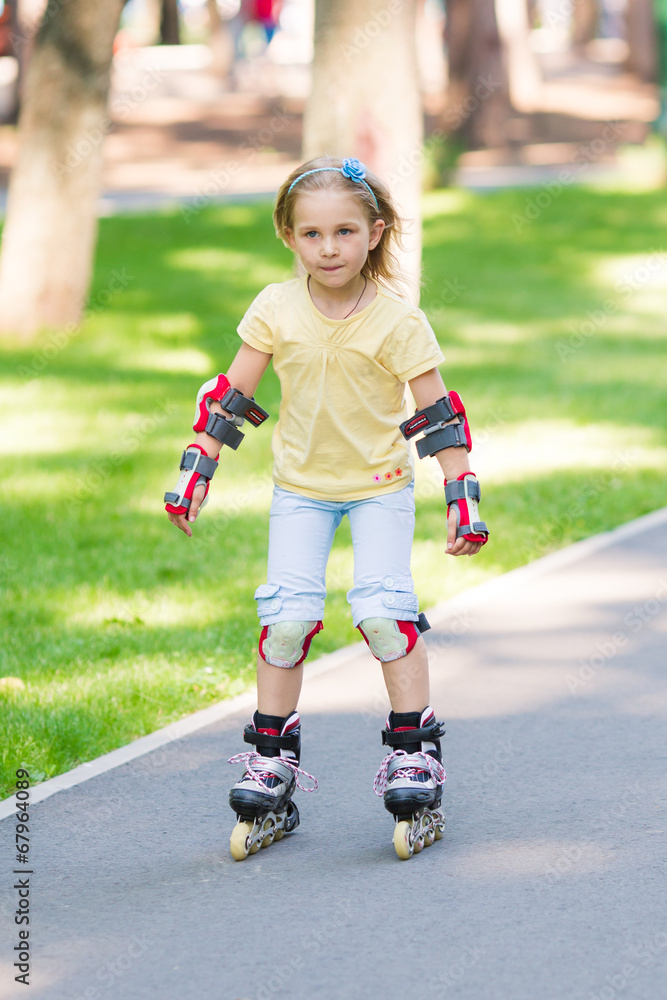 Fototapeta premium Little girl rollerskating in the park