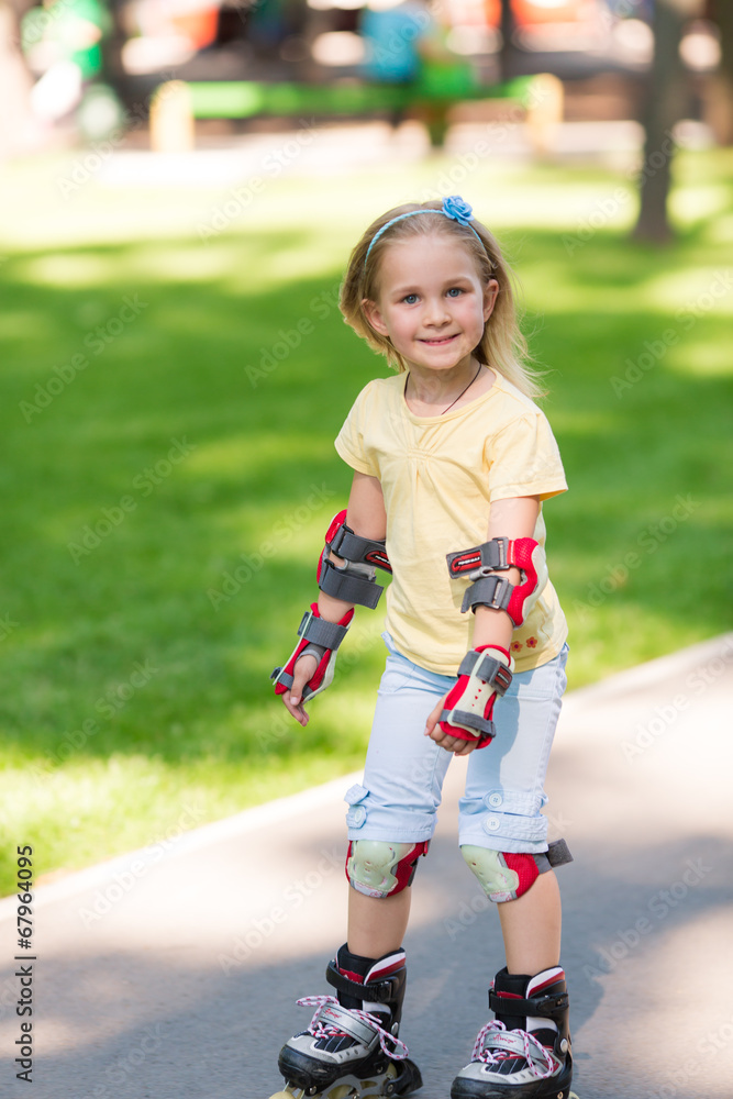 Fototapeta premium Little girl rollerskating in the park