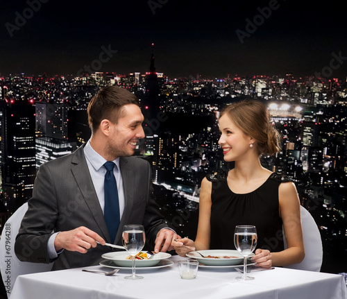 smiling couple eating main course at restaurant