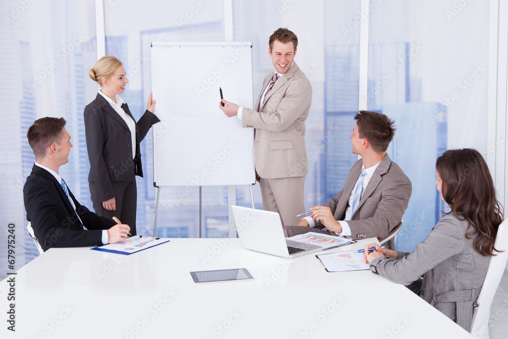 Businessman Giving Presentation To Colleagues In Office Businessman Giving Presentation To Colleagues In Office