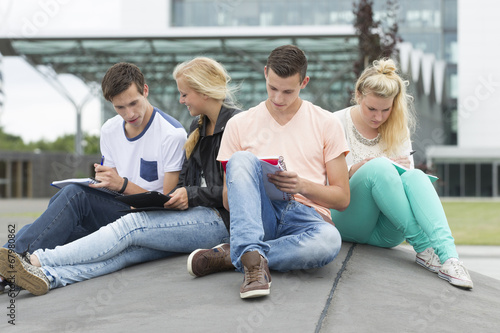 Four students are learning while sitting on the ground