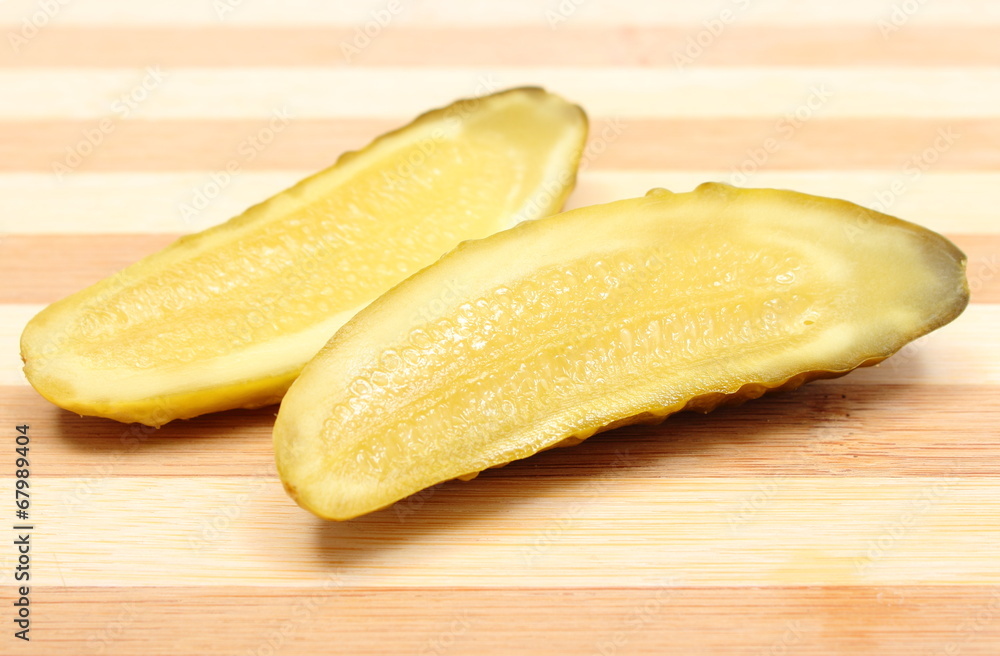 Marinated pickled cucumber lying on wooden cutting board Marinated pickled cucumber lying on wooden cutting board