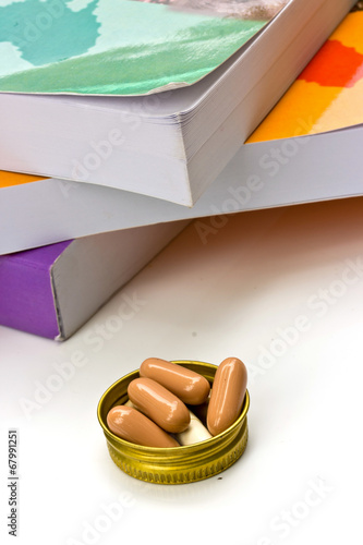 book and capsule pills on white background