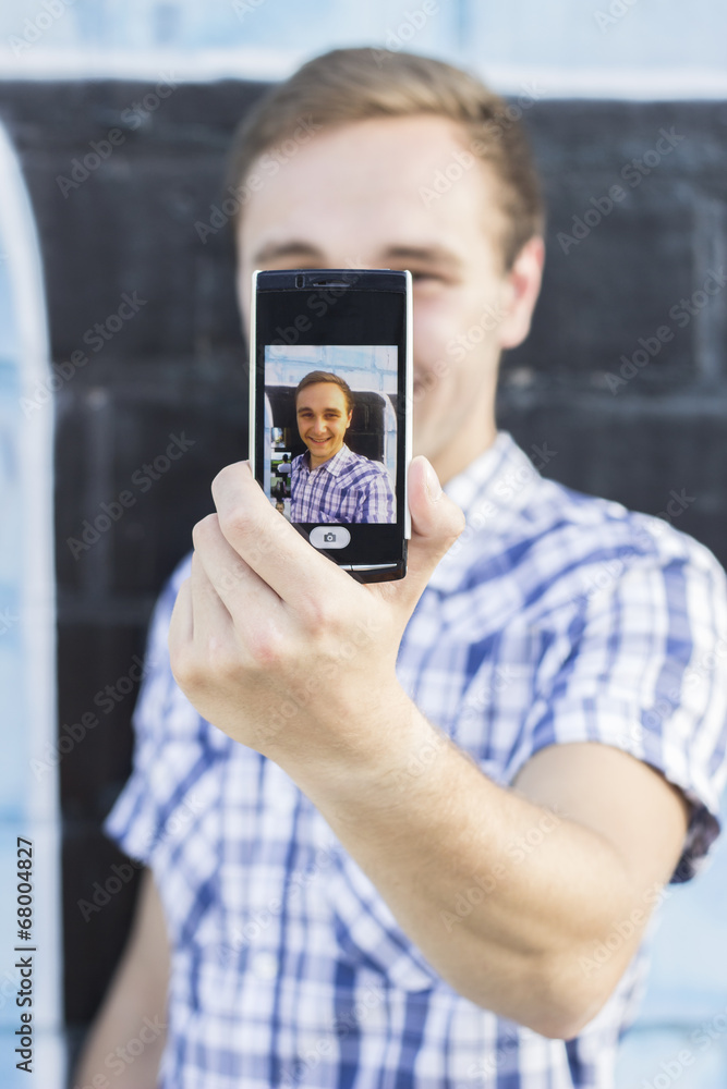 Young fashionable hipster man with sunglasses taking a selfie