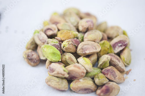 A heap of pistachio nuts on a white background on a sunny day.
