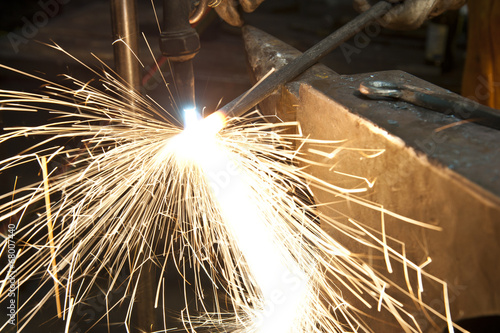 Schilderij op canvas A metal fabricator utilizing a torch to heat up a piece of metal in order to shape it