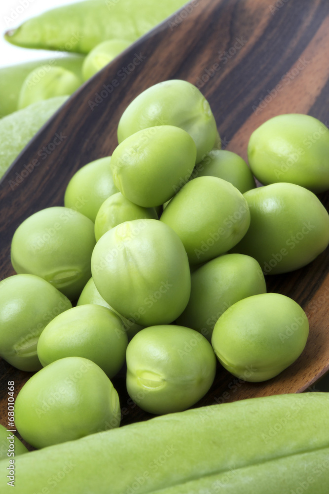 Fresh peas on wooden spoon with pods background Fresh peas on wooden spoon with pods background