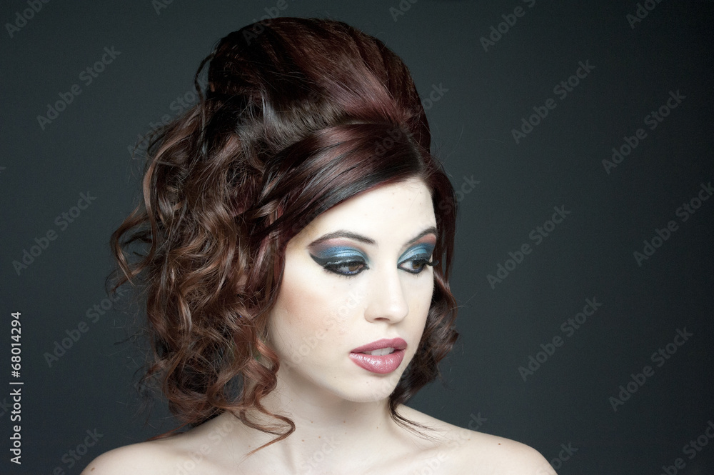 Fototapeta premium A beautiful young model with fashion hair and makeup in a studio.