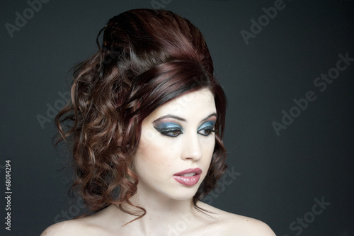 A beautiful young model with fashion hair and makeup in a studio.