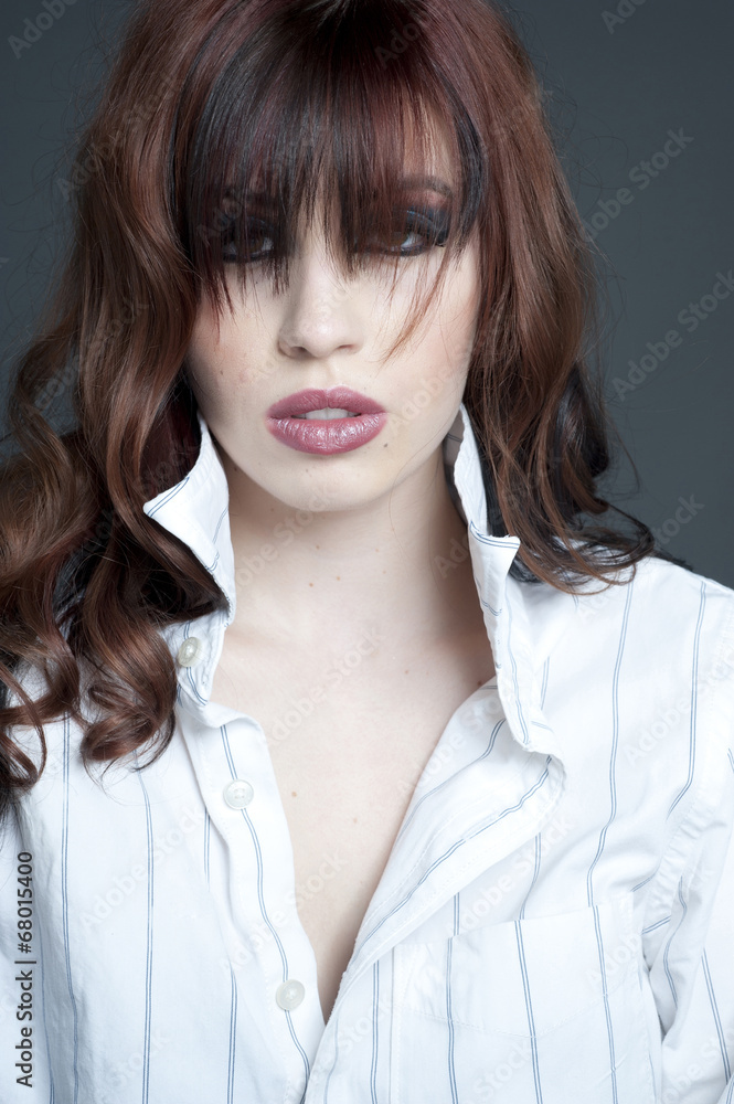 A beautiful young model wearing a button up white t-shirt posing in a studio. A beautiful young model wearing a button up white t-shirt posing in a studio.