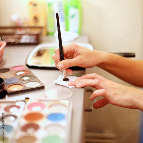 Visagiste's hand taking cosmetic paints with brush