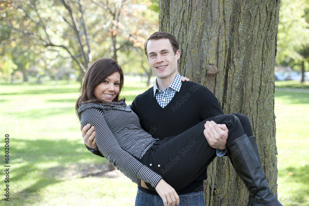 A young man carrying his wife at the park on a sunny day. A young man carrying his wife at the park on a sunny day.