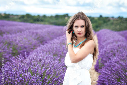 Beautiful girl with green eyes enjoying the scent of lavender