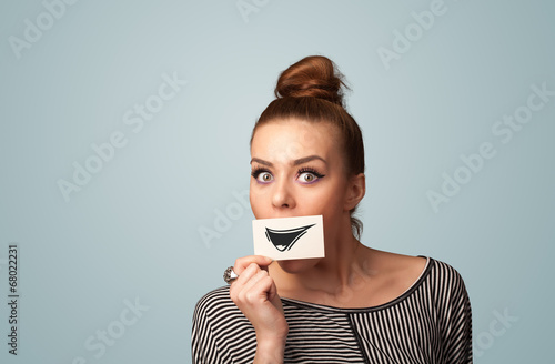 Happy cute girl holding paper with funny smiley drawing