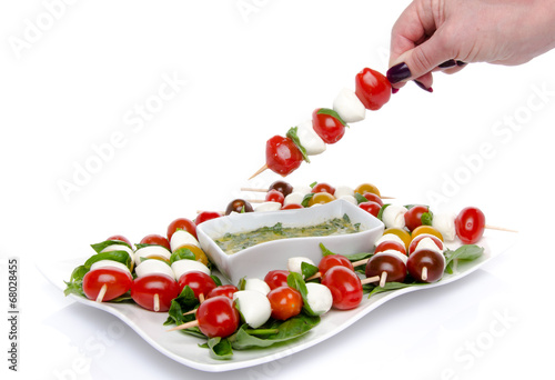 Fotografi Hand dipping a skewer of cherry tomatoes and mozzarella in a vin