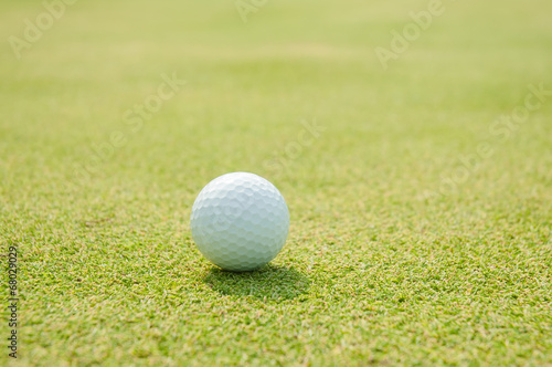 Golfball on grass infront of the green