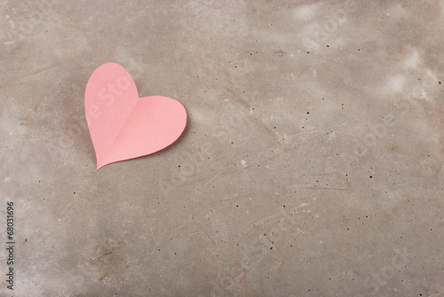 Heart of pink paper on the background of gray concrete
