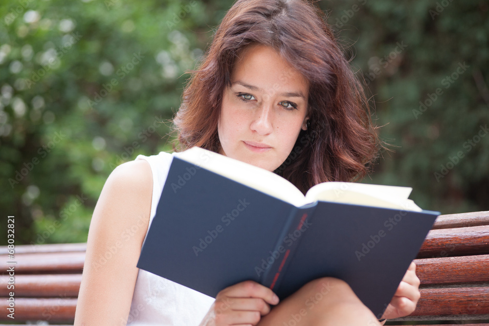 Fototapeta premium Green eyed girl reading a book. In the city.