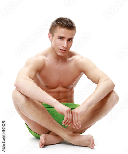 Muscular male model in swimwear sitting on the floor