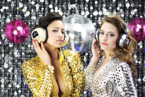 two beautiful sexy disco women in gold and silver catsuits danci