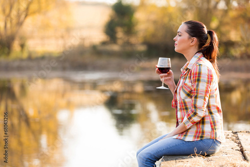 young woman with glass of wine on pier