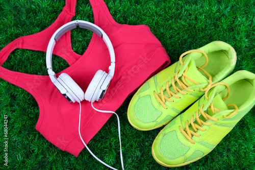 Sport clothes, shoes and headphones on green grass background