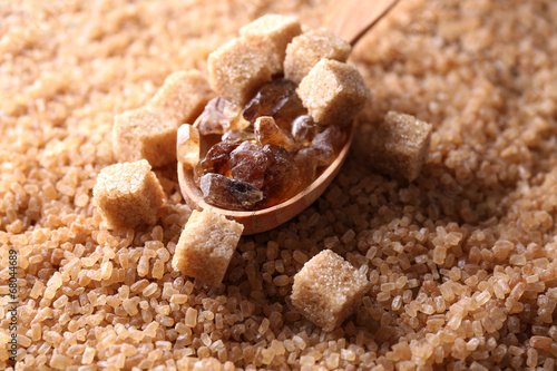 Reed sugar in wooden spoon on brown crystal sugar background photo