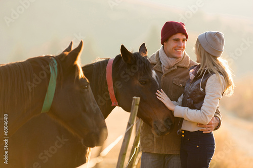 young couple petting a horse in a paddock