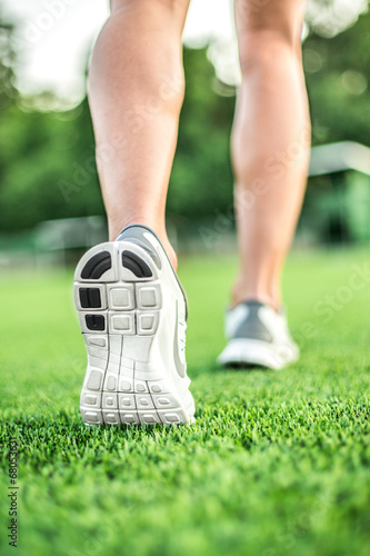 Runner feet running on green grass. closeup on shoe.