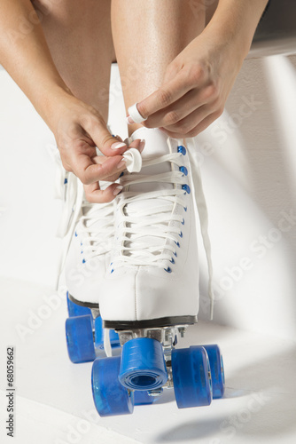 Roller skater tying laces on her quad wheel boots