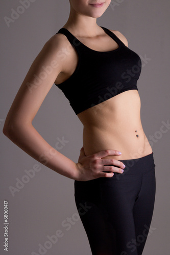 slim woman's body in sports wear over grey