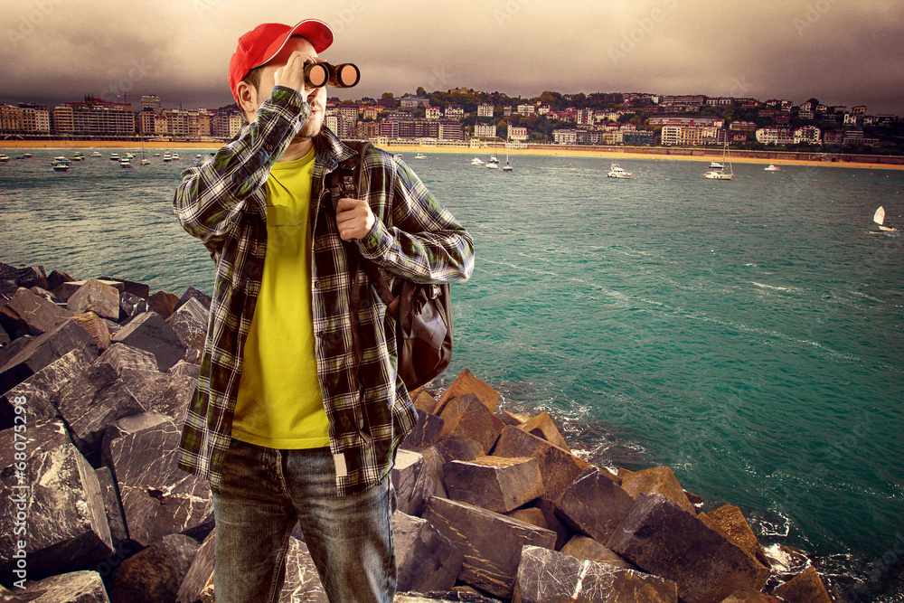 Man climber with backpack looking in binocular at horizon