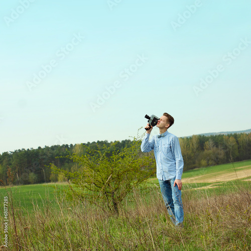 Hipster guy shooting a film on an old vintage movie camera