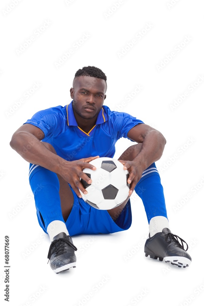 Football player in blue sitting with ball Football player in blue sitting with ball