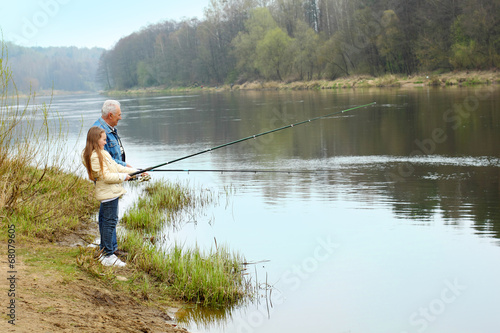 Grandfather and granddaughter are fishing