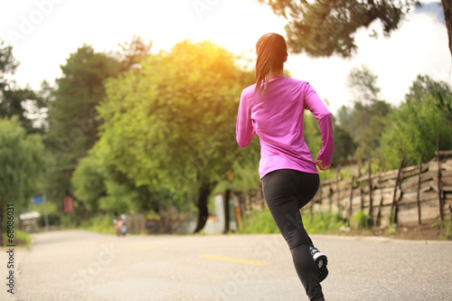 young woman runner athlete running on country road