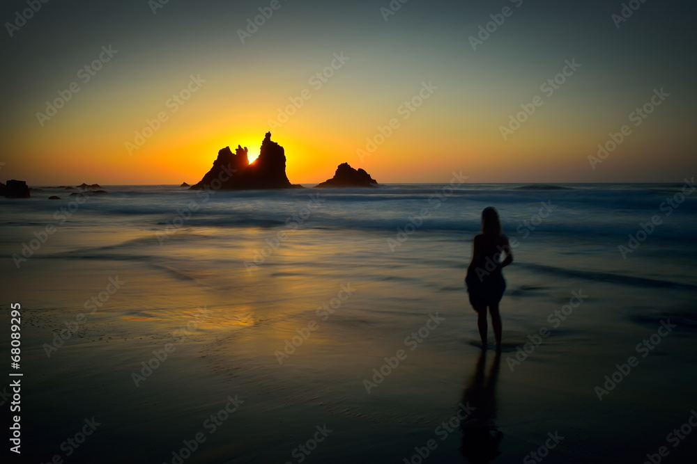 young woman silhouette on the beach at sunset