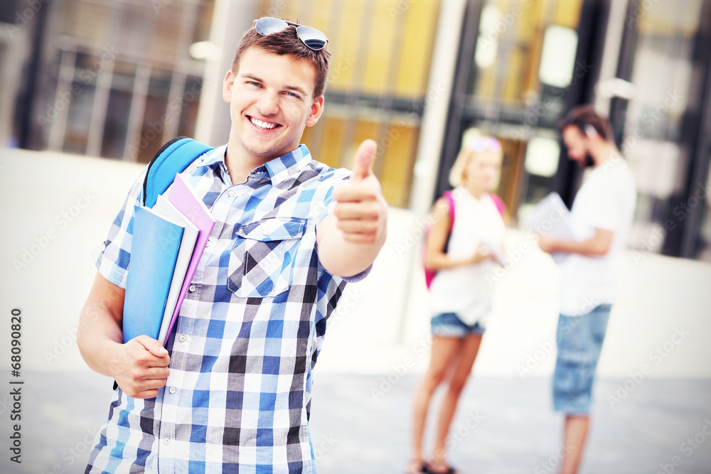 Handsome student showing ok sign in the campus Handsome student showing ok sign in the campus